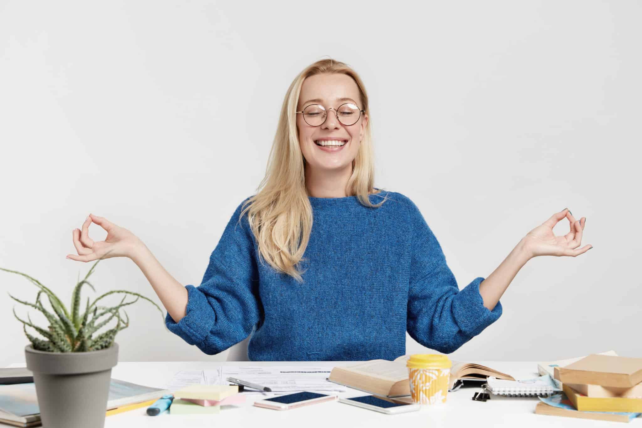 A woman in a meditative post at a desk, representing how to be a good manager.